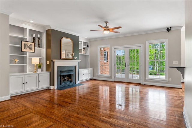 unfurnished living room with crown molding, a fireplace with flush hearth, ceiling fan, and wood finished floors