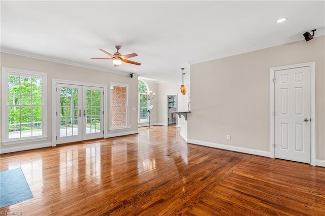 unfurnished living room with french doors, wood finished floors, baseboards, ceiling fan with notable chandelier, and ornamental molding