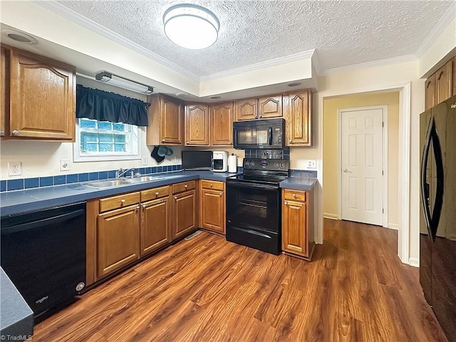 kitchen with a textured ceiling, ornamental molding, black appliances, dark wood-type flooring, and sink