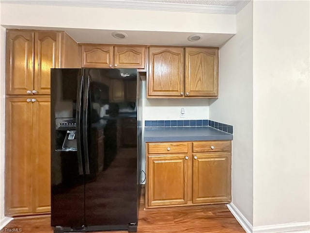 kitchen featuring black refrigerator with ice dispenser, crown molding, and dark hardwood / wood-style floors