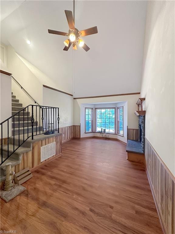 living room featuring wood walls, ceiling fan, high vaulted ceiling, and dark hardwood / wood-style flooring