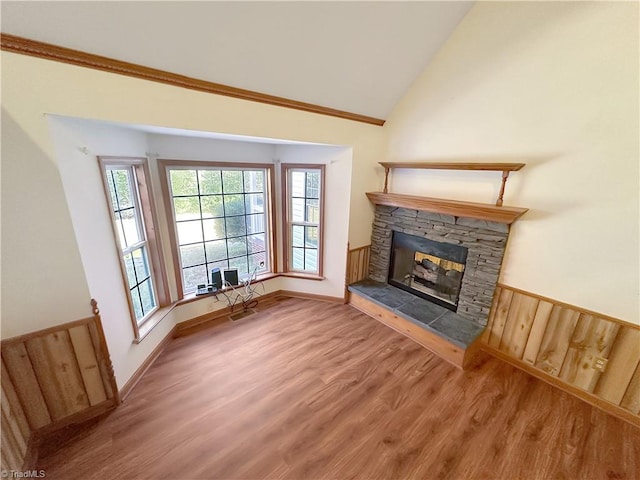 unfurnished living room featuring lofted ceiling, ornamental molding, a fireplace, and hardwood / wood-style flooring