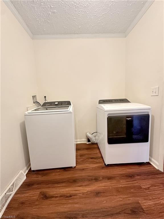 washroom with dark wood-type flooring, a textured ceiling, ornamental molding, and separate washer and dryer