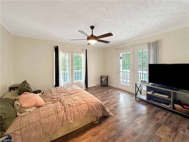 bedroom with access to exterior, dark wood-type flooring, multiple windows, and ceiling fan