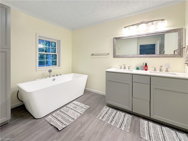 bathroom with a washtub, hardwood / wood-style floors, crown molding, vanity, and a textured ceiling