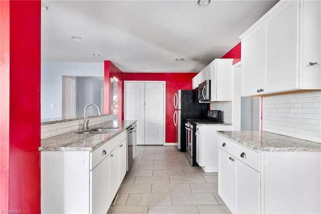 kitchen featuring white cabinetry, appliances with stainless steel finishes, sink, and light stone countertops