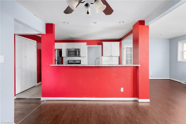 kitchen featuring tasteful backsplash, stainless steel appliances, white cabinetry, dark wood-type flooring, and kitchen peninsula