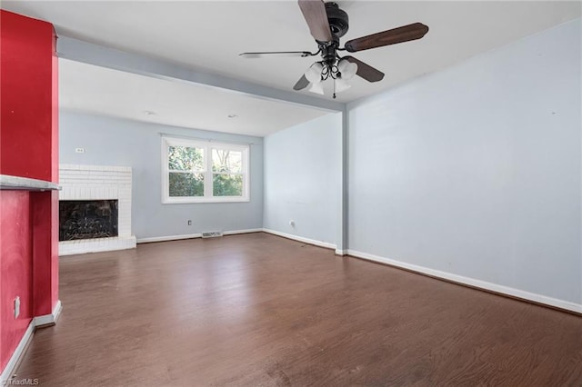 unfurnished living room featuring a brick fireplace, dark wood-type flooring, and ceiling fan