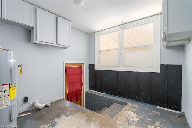 clothes washing area with electric water heater and cabinets