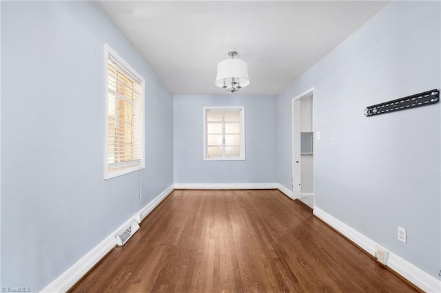 unfurnished dining area with dark wood-type flooring and an inviting chandelier