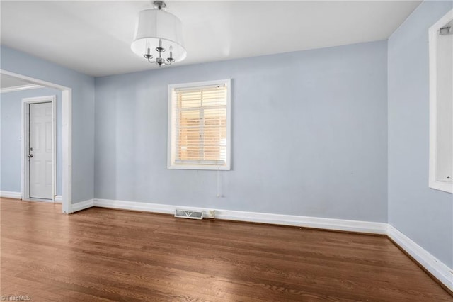 spare room featuring hardwood / wood-style floors and a chandelier