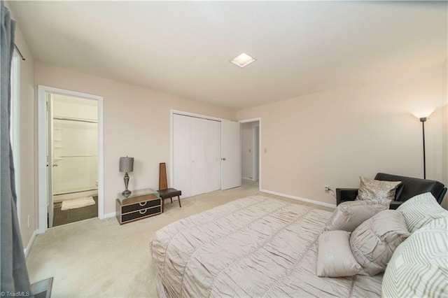 carpeted bedroom with ensuite bathroom and a closet