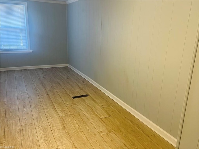 empty room with visible vents, light wood-style flooring, and baseboards