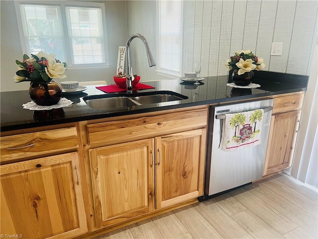 kitchen featuring dark countertops, light wood finished floors, a sink, and dishwasher