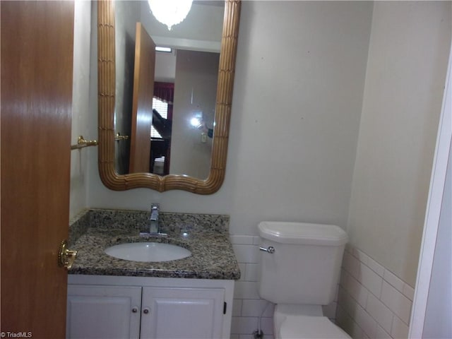 bathroom with vanity, tile walls, and toilet