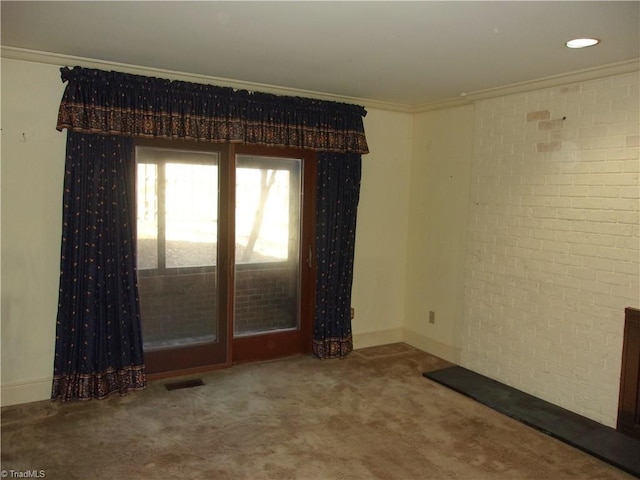 carpeted spare room featuring ornamental molding and brick wall