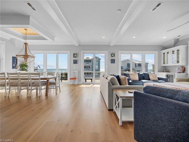 living room featuring a wealth of natural light, beamed ceiling, and light wood-type flooring