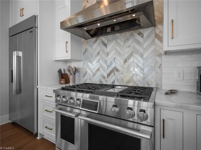 kitchen featuring white cabinetry, ventilation hood, dark wood-type flooring, and premium appliances