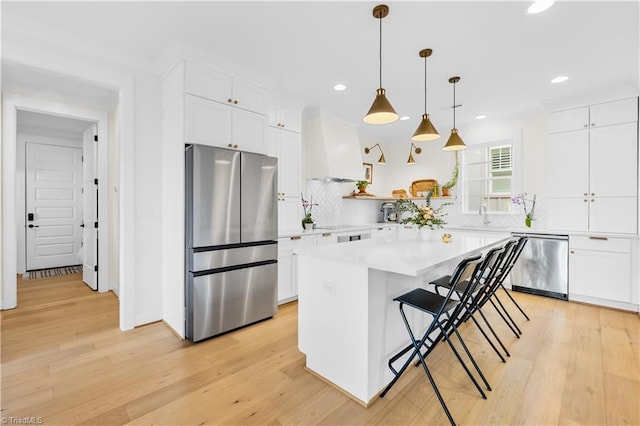 kitchen featuring white cabinetry, decorative light fixtures, a center island, a kitchen breakfast bar, and stainless steel appliances