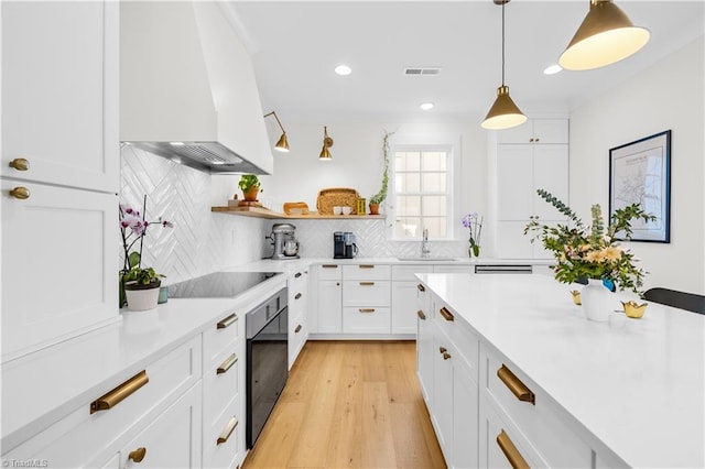 kitchen featuring pendant lighting, white cabinetry, premium range hood, and backsplash