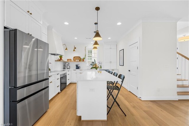 kitchen featuring stainless steel fridge, hanging light fixtures, a kitchen bar, white cabinets, and a kitchen island