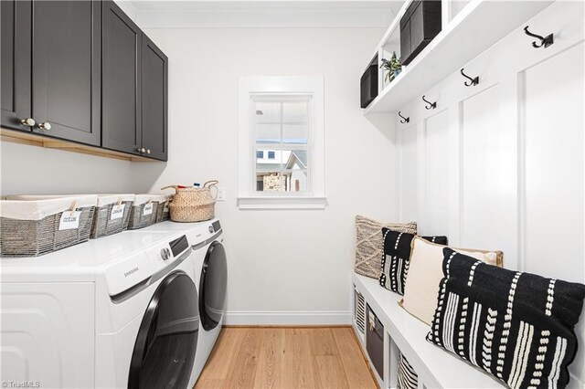 clothes washing area featuring cabinets, washing machine and clothes dryer, and light hardwood / wood-style floors