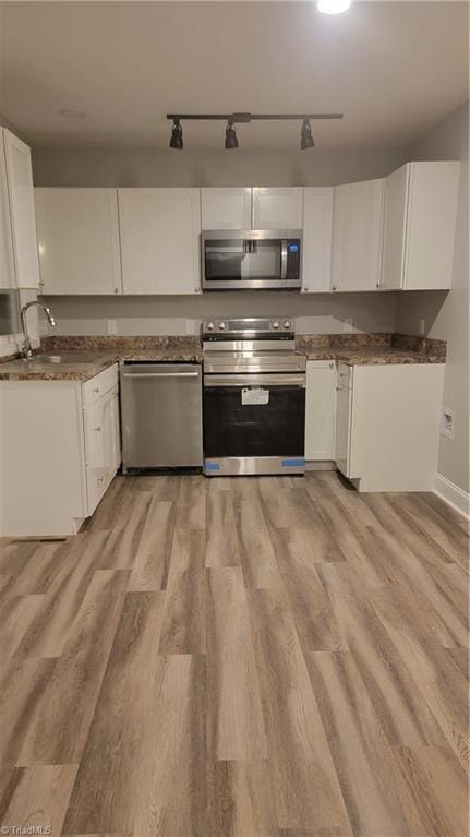 kitchen featuring sink, white cabinets, light hardwood / wood-style floors, and appliances with stainless steel finishes