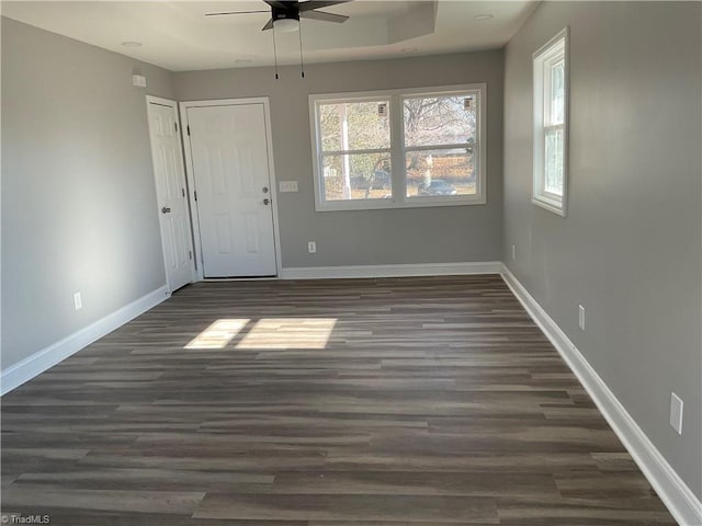 spare room featuring dark hardwood / wood-style flooring, a tray ceiling, and ceiling fan