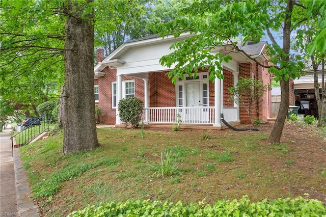 view of front of property with brick siding, covered porch, and a chimney