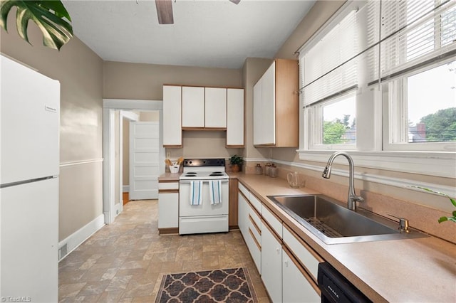 kitchen featuring white appliances, a sink, a ceiling fan, stone finish flooring, and baseboards