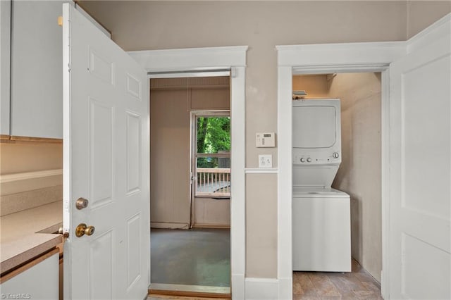 laundry area featuring stacked washer / dryer and baseboards
