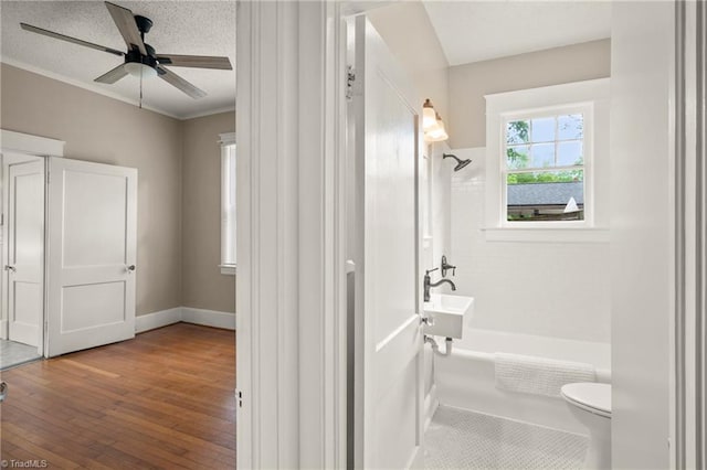 full bathroom featuring toilet, wood finished floors, shower / bath combination, a ceiling fan, and a textured ceiling