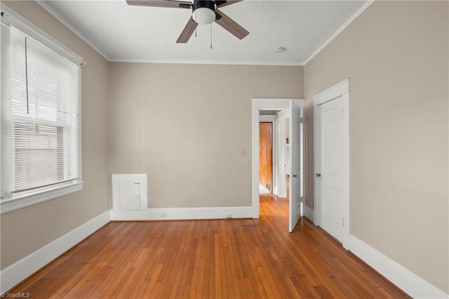 unfurnished bedroom with hardwood / wood-style flooring, multiple windows, crown molding, and baseboards
