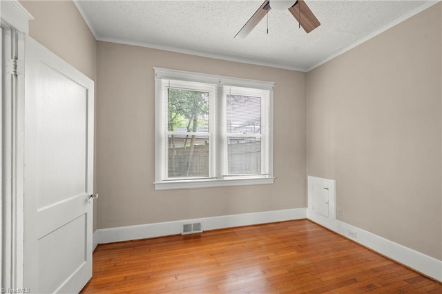 spare room featuring a ceiling fan, light wood-style floors, a textured ceiling, baseboards, and crown molding