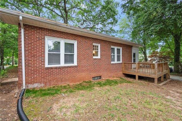 view of home's exterior featuring a wooden deck and brick siding