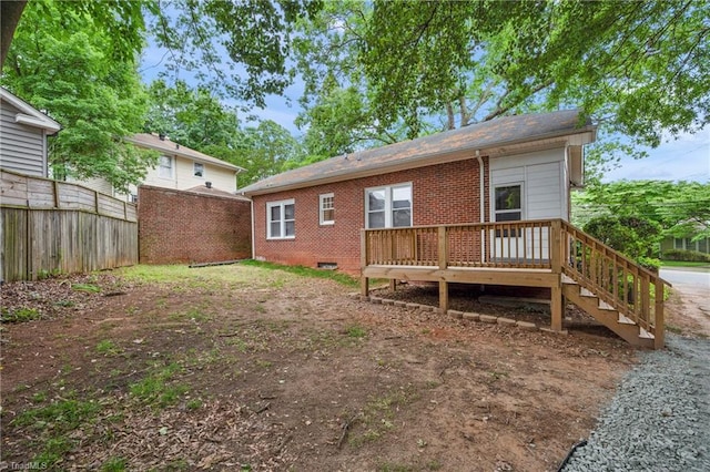 back of house with a wooden deck, fence, brick siding, and roof with shingles