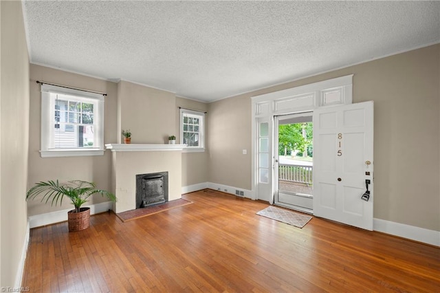 entrance foyer with hardwood / wood-style flooring, plenty of natural light, crown molding, baseboards, and a textured ceiling