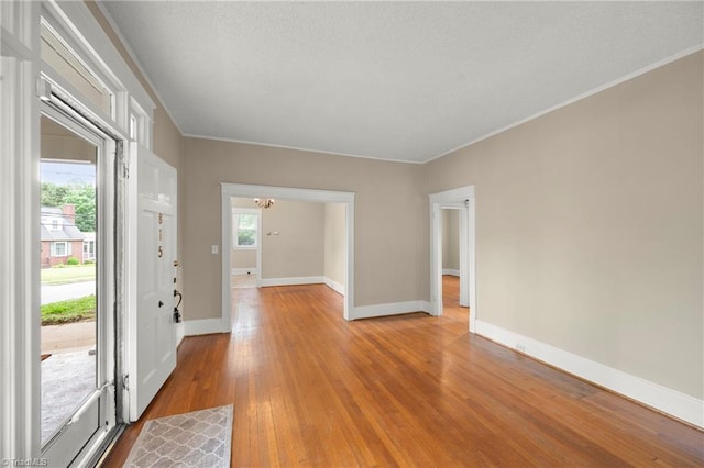 foyer featuring wood finished floors, baseboards, and crown molding