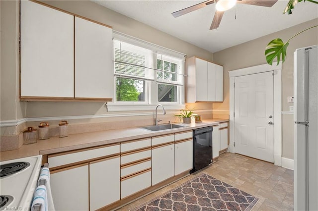 kitchen featuring dishwasher, a sink, light countertops, freestanding refrigerator, and white cabinetry