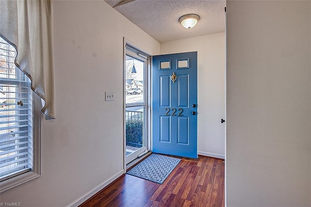 foyer entrance with a textured ceiling and dark hardwood / wood-style flooring