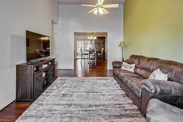 living room featuring dark hardwood / wood-style floors, ceiling fan with notable chandelier, and a high ceiling