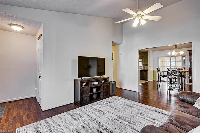 living room with vaulted ceiling, a textured ceiling, ceiling fan with notable chandelier, and dark hardwood / wood-style floors