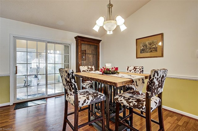 dining room featuring dark hardwood / wood-style floors, vaulted ceiling, and a notable chandelier