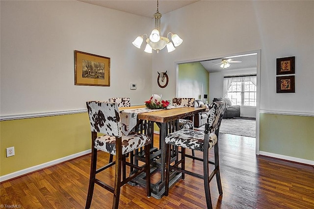 dining room featuring ceiling fan with notable chandelier, wood-type flooring, and lofted ceiling