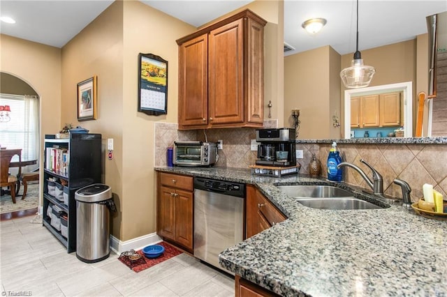 kitchen with backsplash, sink, decorative light fixtures, dark stone countertops, and dishwasher