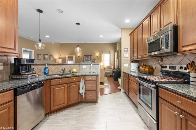 kitchen featuring appliances with stainless steel finishes, dark stone counters, plenty of natural light, and pendant lighting