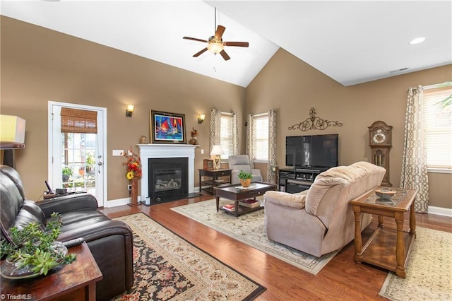 living room with hardwood / wood-style floors, ceiling fan, and high vaulted ceiling