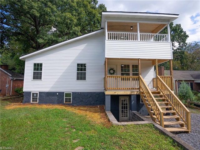 rear view of property featuring a lawn and a balcony