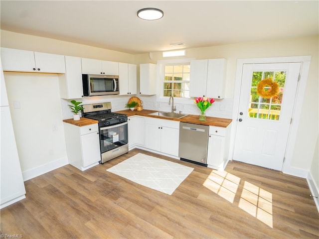 kitchen with stainless steel appliances, white cabinets, plenty of natural light, and butcher block countertops