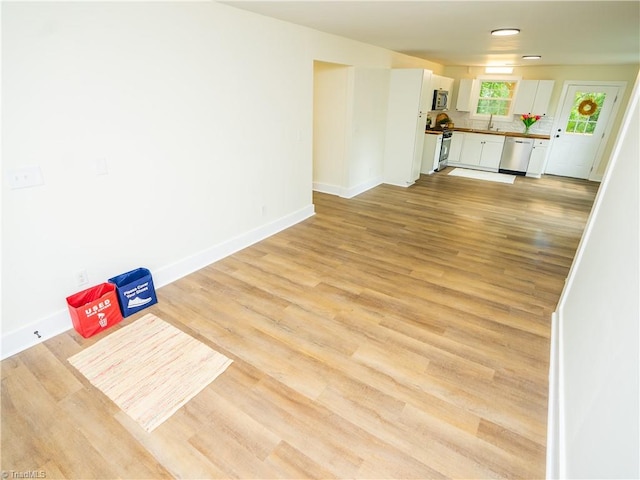 unfurnished living room with sink and light wood-type flooring